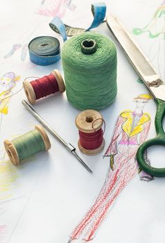 Spools of thread for sewing on the background of the sketch clothing