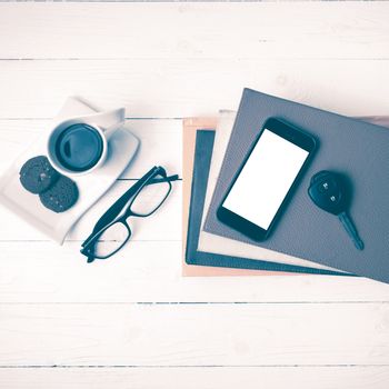 coffe cup with cookie,phone,car key,eyeglasses and stack of book on white wood table vintage style