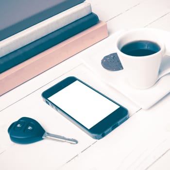 coffe cup with cookie,phone,car key and stack of book on white wood table vintage style
