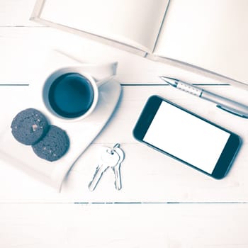 coffee cup with cookie,phone,notebook and key on white wood table vintage style