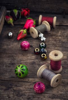 Beads,thread on  background of rosebuds on the board in vintage style