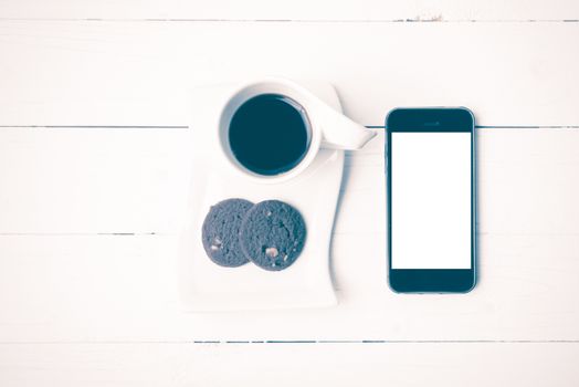 coffee cup with cookie and phone on white wood background vintage style