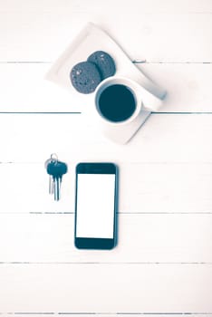 coffee cup with cookie,phone and key on white wood table vintage style