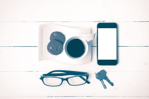 coffee cup with cookie,phone,eyeglasses and key on white wood background vintage style