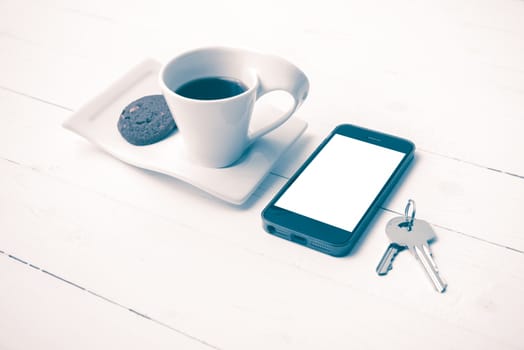 coffee cup with cookie,phone and key on white wood table vintage style