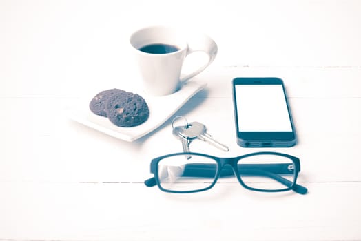 coffee cup with cookie,phone,eyeglasses and key on white wood background vintage style