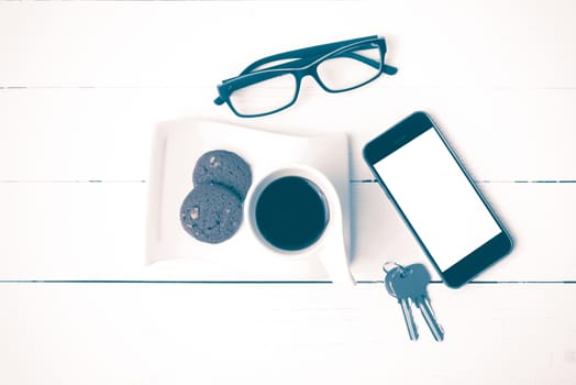 coffee cup with cookie,phone,eyeglasses and key on white wood background vintage style