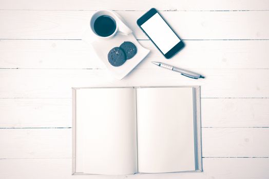 coffee cup with cookie,phone with notebook and pen on white wood table vintage style