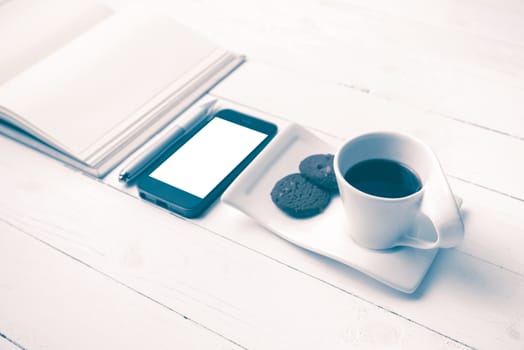 coffee cup with cookie,phone with notebook and pen on white wood table vintage style