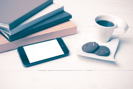 coffe cup with cookie,phone and stack of book on white wood table vintage style