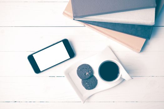 coffe cup with cookie,phone and stack of book on white wood table vintage style