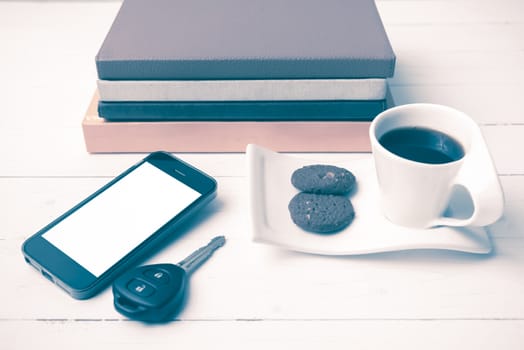 coffe cup with cookie,phone,car key and stack of book on white wood table vintage style