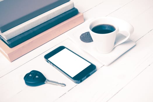 coffe cup with cookie,phone,car key and stack of book on white wood table vintage style