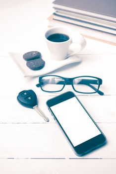 coffe cup with cookie,phone,car key,eyeglasses and stack of book on white wood table vintage style