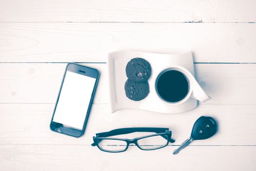 coffee cup with cookie,phone,eyeglasses and car key on white wood table vintage style