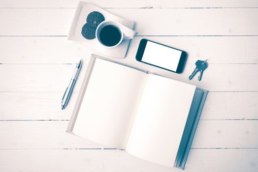 coffee cup with cookie,phone,notebook and key on white wood table vintage style