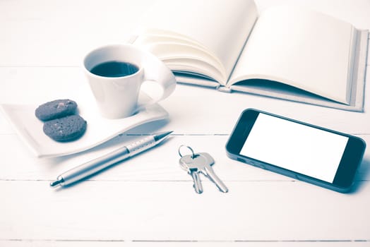 coffee cup with cookie,phone,notebook and key on white wood table vintage style