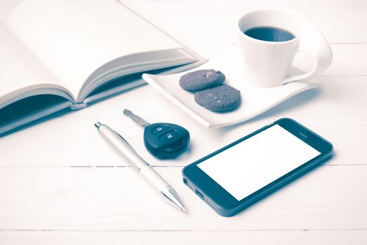 coffee cup with cookie,phone,open notebook and car key on white wood table vintage style