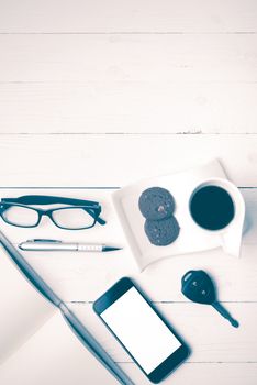 coffee cup with cookie,phone,open notebook,car key and eyeglasses on white wood table vintage style