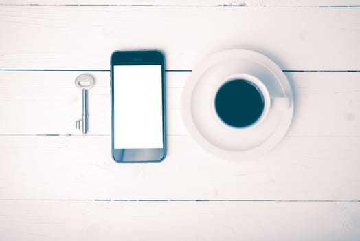 coffee cup with phone and key on white wood table vintage style