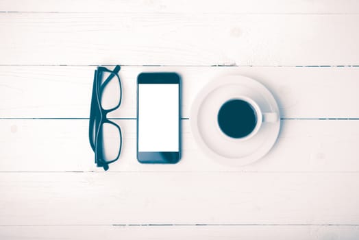 coffee cup with phone and eyeglasses on white wood table vintage style