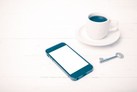 coffee cup with phone and key on white wood table vintage style