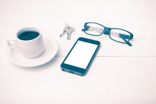 coffee cup with phone, eyeglasses and key on white wood table vintage style