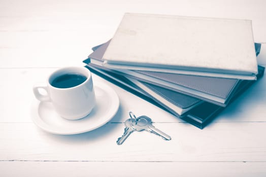 coffee cup,key and stack of book on white wood table vintage style