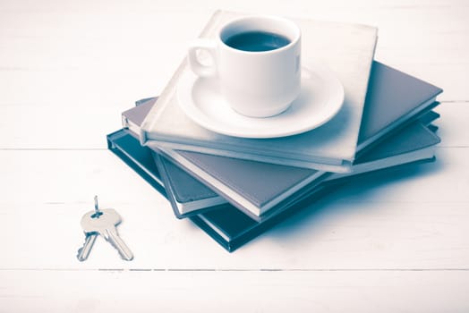 coffee cup,key and stack of book on white wood table vintage style