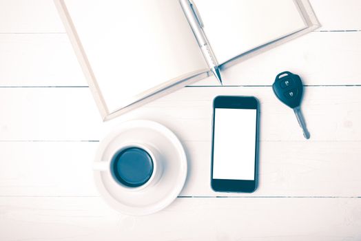coffee cup with phone,car key and open notebook on white wood table vintage style