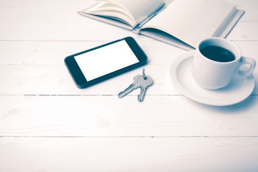 coffee cup with phone, key and open notebook on white wood table vintage style