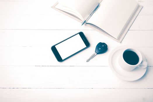 coffee cup with phone,car key and open notebook on white wood table vintage style