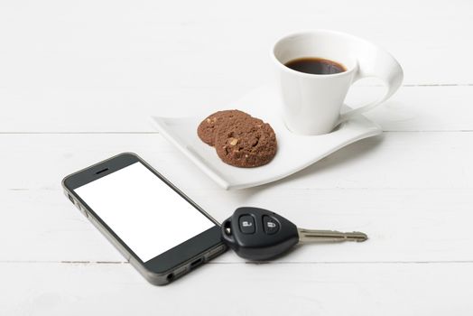 coffee cup with cookie,phone and car key on white wood table