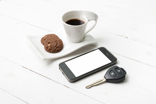 coffee cup with cookie,phone and car key on white wood table