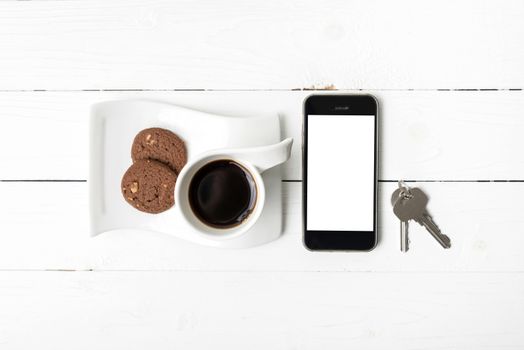 coffee cup with cookie,phone and key on white wood table