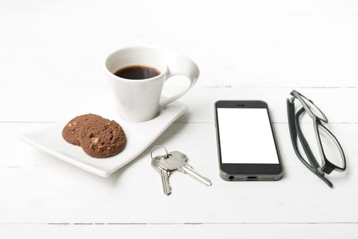coffee cup with cookie,phone,eyeglasses and key on white wood background