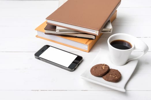 coffe cup with cookie,phone and stack of book on white wood table