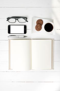 coffee cup with cookie,phone,notebook and eyeglasses on white wood table