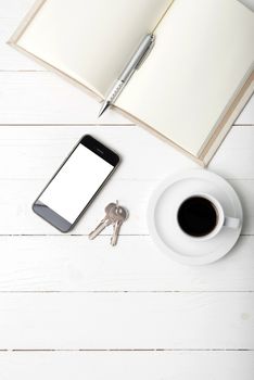 coffee cup with phone, key and open notebook on white wood table