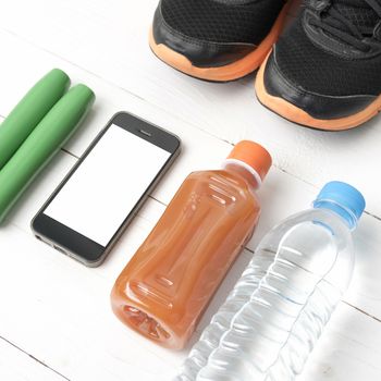 fitness equipment : running shoes,jumping rope,water,juice and phone on white wood background