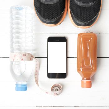 fitness equipment:running shoes,measuring tape,water,juice and phone on white wood background