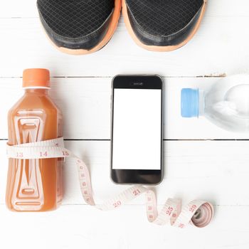 fitness equipment:running shoes,measuring tape,water,juice and phone on white wood background