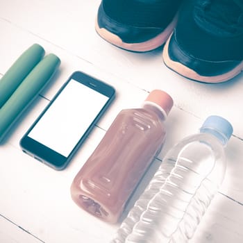 fitness equipment : running shoes,jumping rope,water,juice and phone on white wood background vintage style