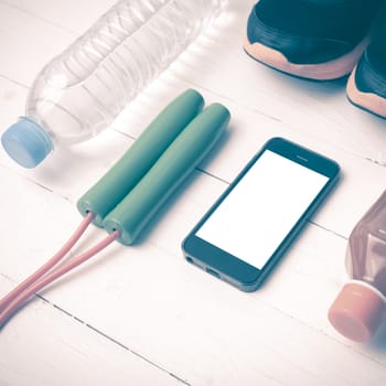 fitness equipment : running shoes,jumping rope,water,juice and phone on white wood background vintage style