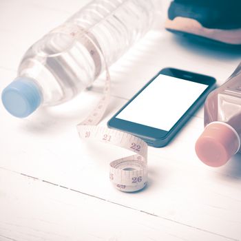 fitness equipment:running shoes,measuring tape,water,juice and phone on white wood background vintage style