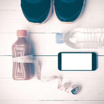 fitness equipment:running shoes,measuring tape,water,juice and phone on white wood background vintage style