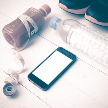 fitness equipment:running shoes,measuring tape,water,juice and phone on white wood background vintage style