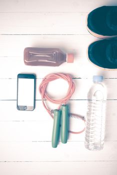 fitness equipment : running shoes,jumping rope,water,juice and phone on white wood background vintage style