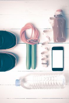 fitness equipment:running shoes,phone,measuring tape,water,juice and jumpong rope on white wood background vintage style