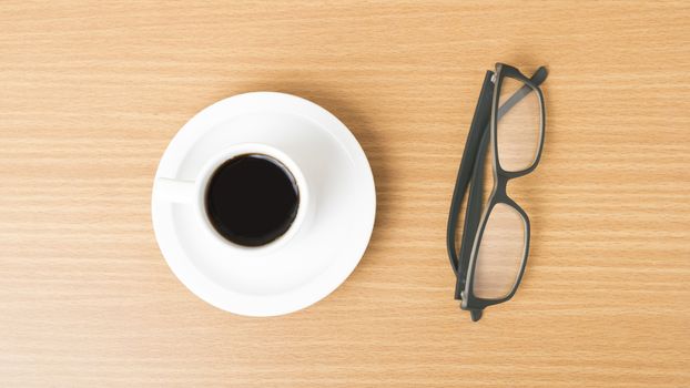 coffee cup and eyeglasses on wood background